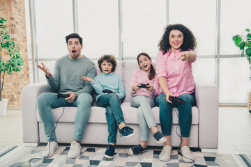 Fototapeta premium Happy family enjoying video games together on a cozy couch in a bright living room