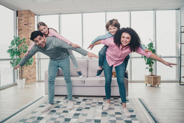 Cheerful family enjoying playful moments indoors with parents and children bonding together in a...