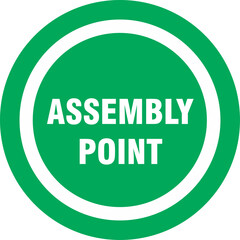 Green circular sign with white inner circle and the text "ASSEMBLY POINT" indicating a designated meeting area