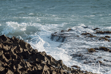 view of a dry coral reef with the waves creating a white foam when hitting the shore