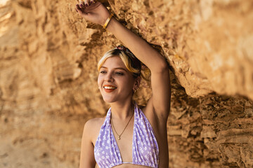 Tourist smiling and leaning on rock formation at la mina beach, paracas national reserve