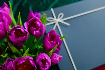 Boxes with gifts and a bouquet of dark purple tulips.Gift Box with Purple Tulips Arrangement.