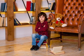 A little boy sits among the books in the library 