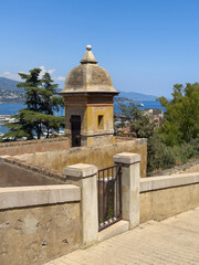Principality of Monaco, France - July 9, 2024: Defensive tower along ramparts of Palace. Forested mountain in back under blue sky