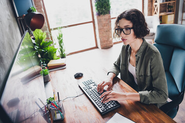 Young professional woman working on computer programming projects in a well-lit modern home office...
