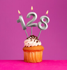 Birthday candle number 128 with cupcake on violet background