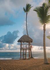 view of a safeguard station made of wood with a red flag next to it facing the ocean on a sunrise