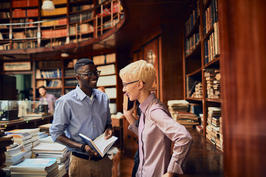 Two young students talking and studying together in a university library