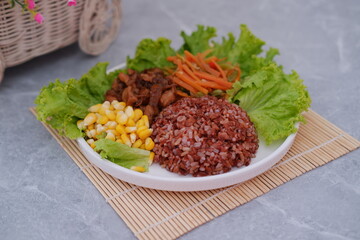 Healthy and balanced meal with red rice, chicken, and fresh vegetables.
