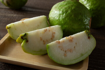 A view of some white guava fruit, featuring one that is cut into wedges.