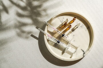  flat lay of various syringes, ampoules, medical gloves, disposable cap arranged on a light background, natural sunlight. Concept of medical preparation or cosmetic procedure setup