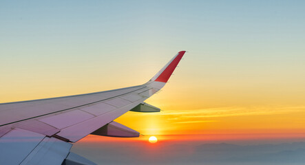Obraz premium Aerial view of along passenger plane wing flying above beautiful sunset.