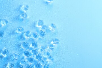 Cubes of clear ice on light blue background, flat lay. Space for text