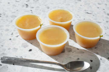 A view of several package cups of apple sauce.