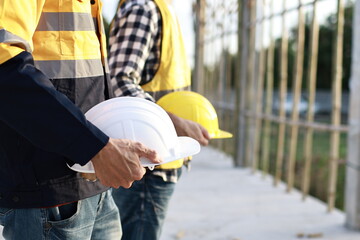 A diverse group of architects, engineers, and business professionals exchange a handshake indoors, symbolizing teamwork, success, and cooperation in a construction industry agreement.