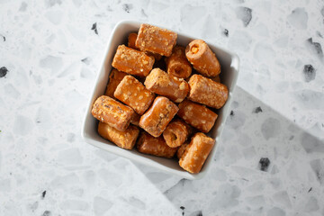A top down view of a pile of cheese filled pretzel snacks, in a small ceramic bowl.
