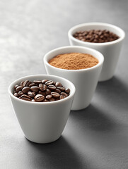 Coffee preparation. Three white ceramic cups stand in a row on a gray table. Cups with coffee beans, ground coffee and cacao. Menu of a coffee shop, cafe.