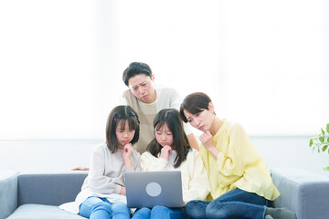 困った表情でパソコンを使う家族
