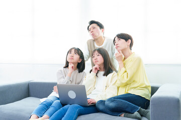 困った表情でパソコンを使う家族