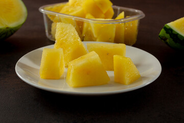 A view of a plate of chopped yellow watermelon chunks.
