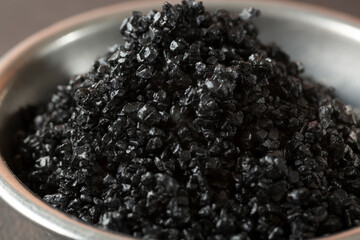 A closeup view of a condiment cup of black sea salt.