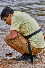 young man squatting by the water