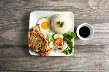A top down view of a plate of broken rice, featuring grilled chicken.