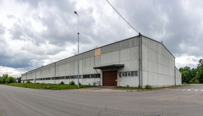 Obraz premium Industrial Warehouse Exterior with Cloudy Sky and Empty Road View