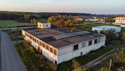 Fototapeta premium Abandoned Industrial Structure Surrounded by Nature at Dusk