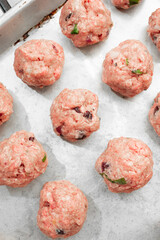 A top down view of raw cranberry meatballs in a baking sheet.