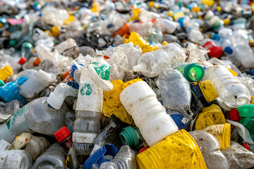 Fototapeta premium A close-up shot of a pile of discarded plastic bottles and containers, showcasing the environmental issue of plastic waste. The bottles are dirty and show signs of weathering.