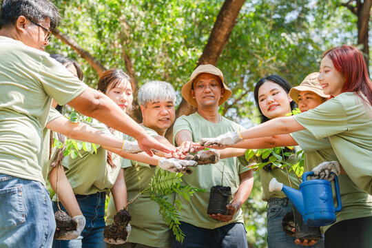 Group of Happy Asian volunteers team in park for charity event with joining hands