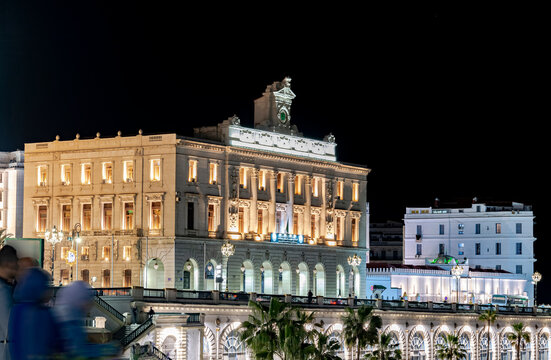 The Algerian Chamber of Commerce and Industry building at night in Algiers, housed in the historic Consular Palace with Neoclassical architecture and bilingual nameplate in Arabic and English.