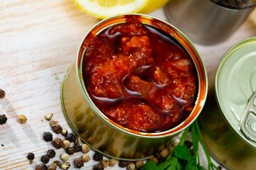 Canned squid in tomato sauce on table