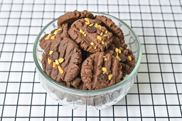 Close up view of cookies with peanut and chocolate chips in glass bowl isolated on white background. Freshly Baked Homemade. perfect for bakery advertisements and dessert menus. Baking rack.