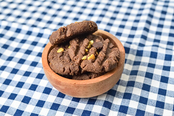 Close up view of cookies with peanut and chocolate chips in little wooden bowl isolated on napkin background. Freshly Baked Homemade. perfect for bakery advertisements and dessert menus.