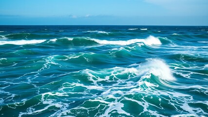 A breathtaking view of powerful ocean waves crashing and churning under a vibrant blue sky on a sunny day.
