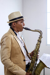 Naklejka premium Side View Of Young Asian Male Playing Jazz Music With Saxophone In The Studio