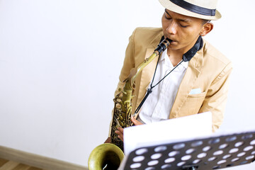 Cropped Shot Of Young Asian Man Playing Jazz Music With Saxophone While Sitting