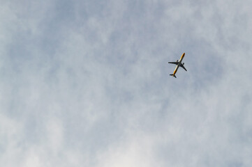 commercial airliner flies overhead on cloudy and cold winter day.