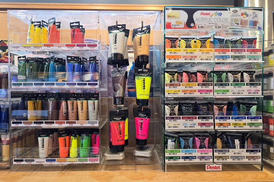 Kuala Lumpur, Malaysia &ndash; Mar 31, 2025: Vibrant selection of Reeves and Pentel acrylic paint tubes in various colors arranged neatly in clear display stands at Kinokuniya bookstore, Suria KLCC.