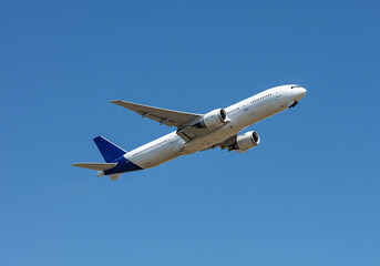 A white and blue airplane flying in a clear blue sky during the daytime with its engines visible well