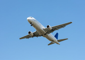 A white airplane with blue tail flying in a clear blue sky during the daytime with landing gear down