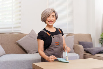 Smiling Asian Women in Apron Cleaning Dust on Table Indoor Home Older Person Housekeeping Work...