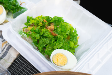 Gado-gado, Indonesian vegetable salad with peanut sauce and boiled egg. In a styrofoam box for take away.