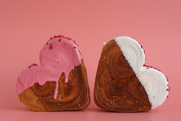 Heart shaped two couple croissants on pink background with copy space. Puff pastry new trendy sweet...