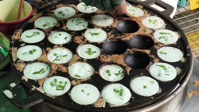 Khanom Khrok is a traditional Thai coconut-rice pancake, famous for its sweet, creamy, and slightly crispy texture. It is cooked in a special cast-iron pan with small round molds