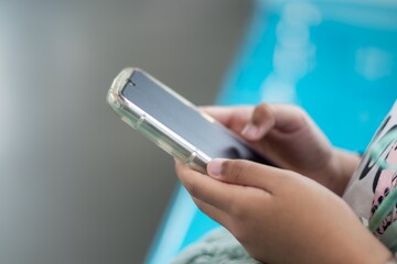 Close up view of a little girl's hand using a smartphone in public transportation