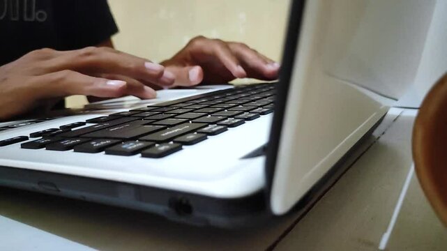Hands moving laptop touchpad on desk