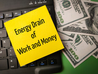 Black keyboard and banknotes with the word Energy Drain of Work and Money on a yellow sticky note